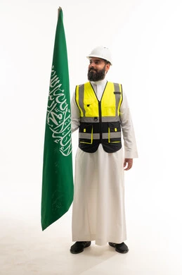 مهندس سعودي يرتدي سترة السلامة ويحمل العلم السعودي