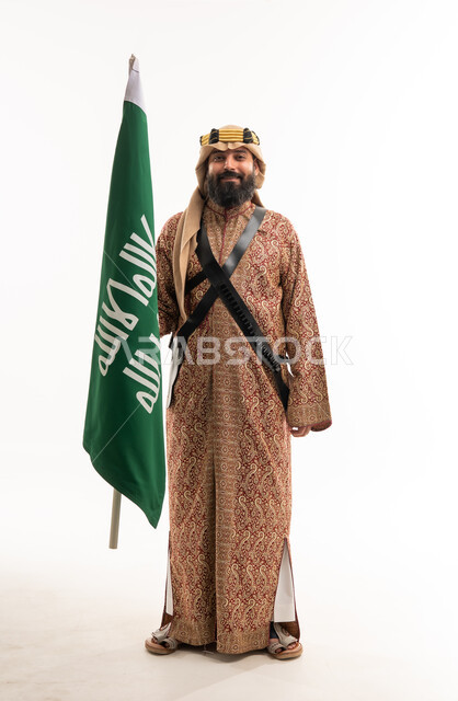رجل سعودي بالزي الشعبي يحمل علم المملكة