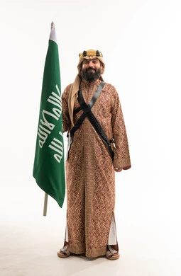 رجل سعودي بالزي الشعبي يحمل علم المملكة