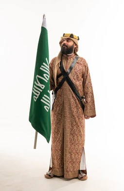 رجل سعودي بالزي التقليدي يحمل علم المملكة العربية السعودية