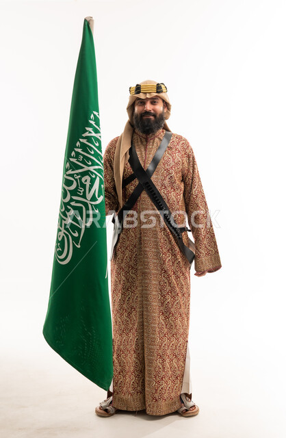 رجل سعودي بالزي التراثي يحمل علم السعودية