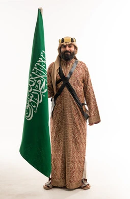 رجل سعودي بالزي التراثي يحمل علم السعودية