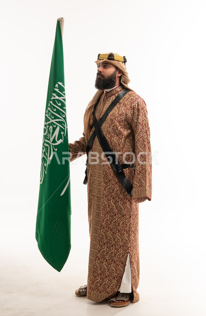 رجل سعودي بالزي التقليدي يحمل العلم الوطني