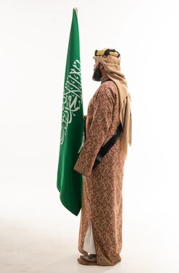 رجل سعودي يحمل العلم الوطني بالزي التراثي التقليدي