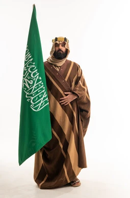 رجل سعودي يحمل العلم بالزي التراثي التقليدي