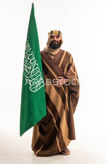 رجل سعودي يحمل العلم الوطني بالفروة الشتوية التقليدية