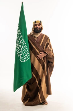 رجل سعودي يحمل العلم الوطني بالفروة الشتوية التقليدية