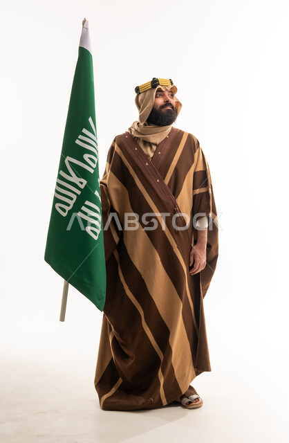 Saudi Man Holding Kingdom Flag in Traditional Farwa