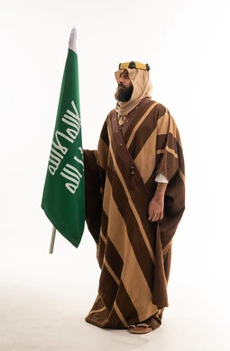 رجل سعودي بالبشت التقليدي يحمل علم السعودية