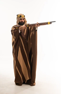 رجل سعودي بالزي التقليدي يصوب بندقية قديمة