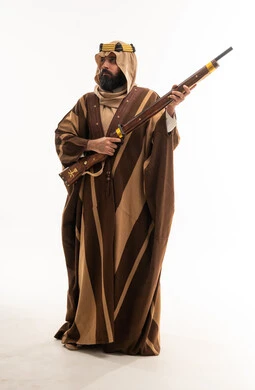 رجل سعودي بالبشت التراثي يحمل بندقية تقليدية