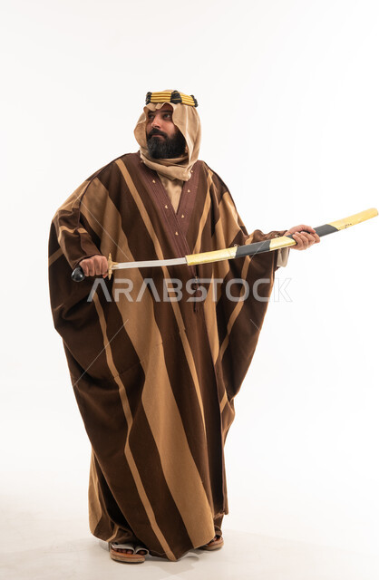 رجل سعودي بالزي التراثي التقليدي يحمل سيفاً عربيًا