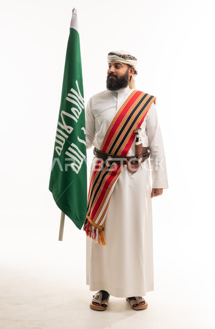 رجل سعودي بالزي النجدي التقليدي يحمل العلم