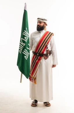 رجل سعودي بالزي النجدي التقليدي يحمل العلم