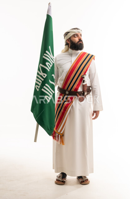 رجل سعودي بالزي الشعبي يحمل علم السعودية