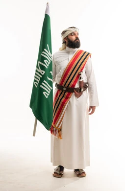 رجل سعودي بالزي الشعبي يحمل علم السعودية