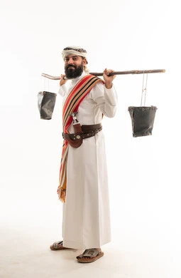 رجل عماني بالزي التقليدي يحمل دلاء الماء