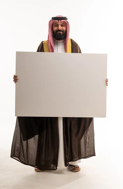 رجل سعودي بالبشت التقليدي يحمل لوحة بيضاء فارغة