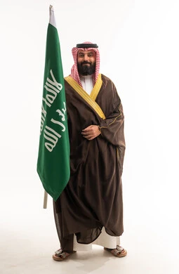 رجل سعودي بالبشت التقليدي يرفع العلم الوطني