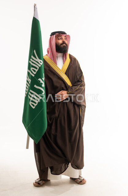 رجل سعودي بالبشت التقليدي يحمل علم المملكة