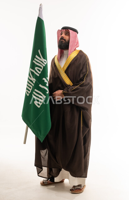 رجل سعودي يحمل العلم بالبشت التقليدي