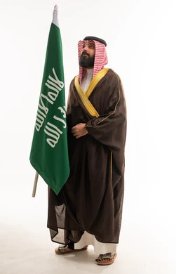 رجل سعودي يحمل العلم بالبشت التقليدي