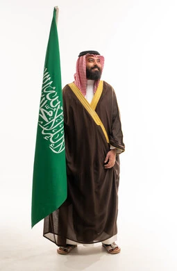 رجل سعودي بالبشت التقليدي مع علم المملكة