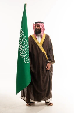 رجل سعودي يحمل العلم الوطني بالزي التقليدي والبشت