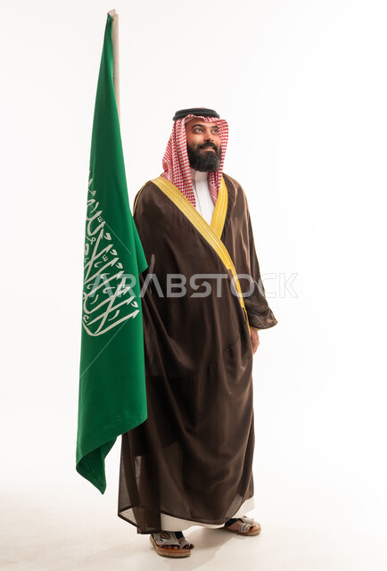 رجل سعودي بالزي الرسمي مع العلم الوطني