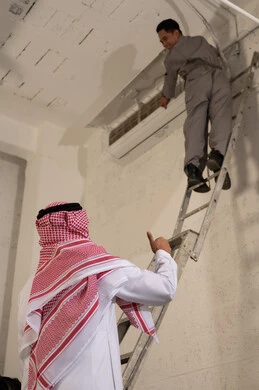 رجل سعودي يشرف على فني يصلح مكيف هواء