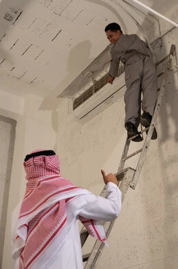 رجل سعودي وفني آسيوي يصلحان مكيف هواء