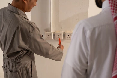 فني يقوم بإصلاح مقابس الكهرباء في منزل سعودي