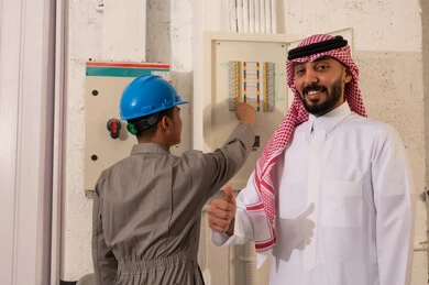 رجل أعمال سعودي وفني كهرباء عند لوحة التوزيع