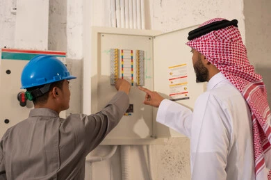 رجل سعودي وفني يفحصان لوحة الكهرباء