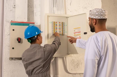 مشرف عماني مع فني كهرباء عند لوحة القواطع