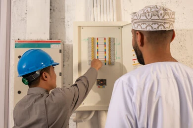 Omani Man and Technician Inspecting Electrical Panel