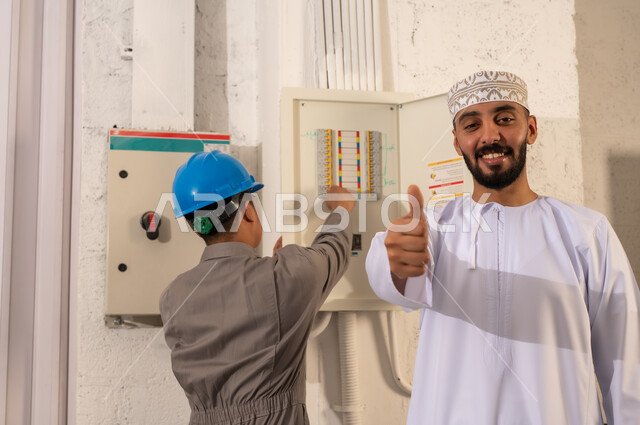 Omani Man with Electrician Working on Electrical Panel