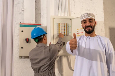 رجل عُماني مع فني صيانة لوحة مفاتيح كهربائية