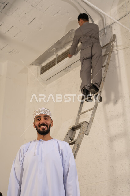Omani Man with Technician Repairing Air Conditioning Unit