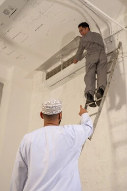 رجل عماني وفني صيانة خلال إصلاح مكيف هواء