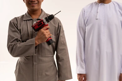 رجل إماراتي وفني يحمل مثقاب كهربائي