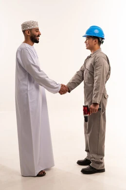 رجل عماني يصافح عامل فني بملابس العمل