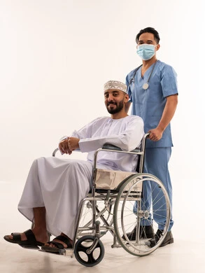 رجل عماني على كرسي متحرك مع ممرض طبي