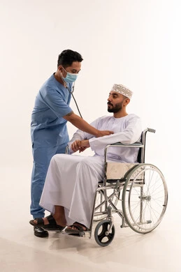 فحص طبي لمريض عماني على كرسي متحرك بخلفية بيضاء
