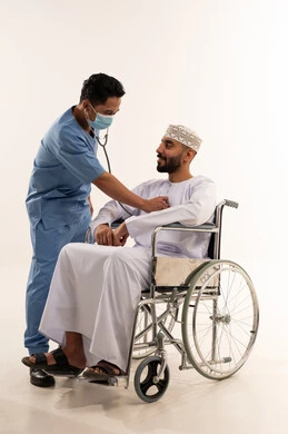 Asian Nurse Examining Omani Patient in Wheelchair