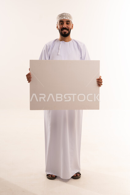 رجل عماني يحمل لوحة إعلانية بيضاء فارغة