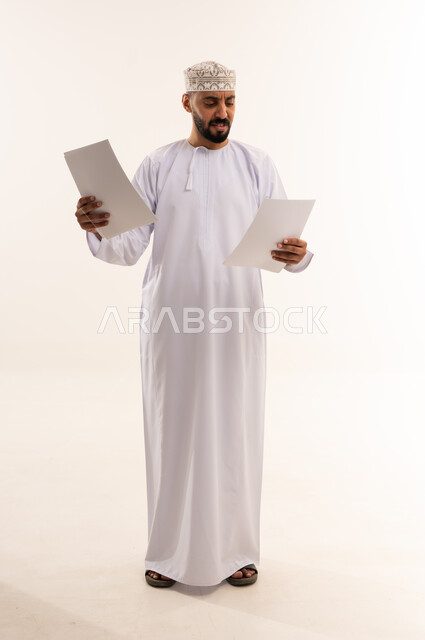 رجل عماني بالزي التقليدي يراجع أوراق عمل