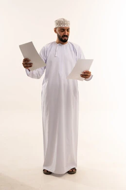 رجل عماني بالزي التقليدي يراجع أوراق عمل