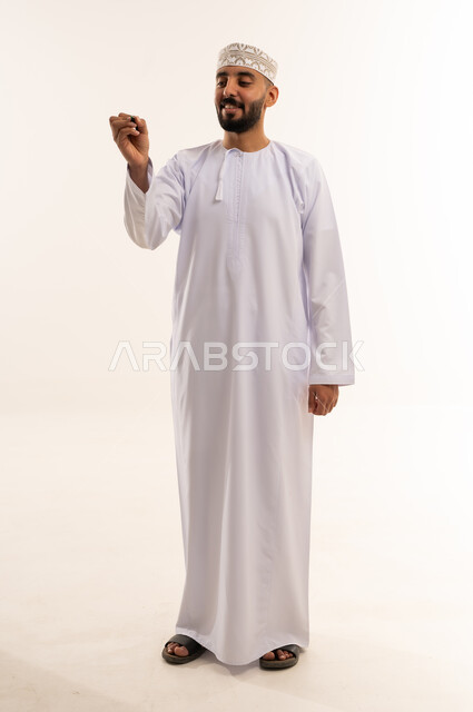 رجل عماني بالزي التقليدي يكتب على خلفية بيضاء