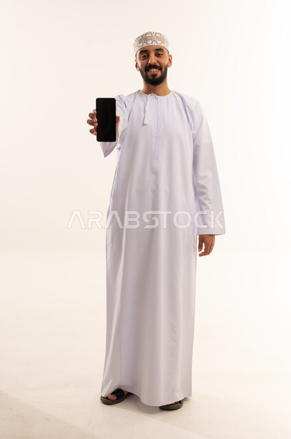 رجل عماني بالزي التقليدي يمسك هاتف ذكي
